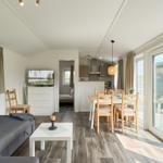 Wohnbereich mit Sofa, Esstisch und Schlafzimmer im Hintergrund.