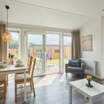 Esszimmer mit Tisch und Stühlen, Blick auf Terrasse mit Garten.