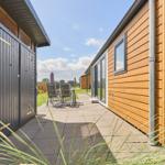 Terrasse mit Sitzgruppe zwischen Holzhäusern unter blauem Himmel.