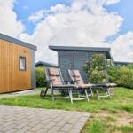 Zwei Liegestühle stehen auf einer Wiese vor einem Holzhaus mit grauem Dach.