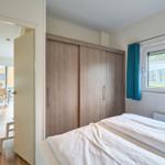 Schlafzimmer mit Doppelbett, Kleiderschrank und Fenster mit Blick nach draußen.