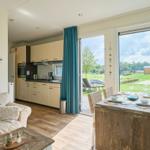 Wohnküche mit Essbereich, großes Fenster und Blick auf Grünfläche.