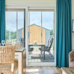 Essbereich mit Blick auf Terrasse und Garten. Sofa und Fernseher im Wohnbereich.