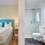 Schlafzimmer mit Bett und Bad mit Dusche und Toilette