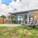 Moderne Ferienhaus mit Terrasse, Liegestühlen und Grillplatz im Grünen.