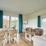 Wohn- und Essbereich mit Sofa, Stühlen und TV. Blick auf Garten.