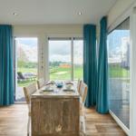 Essbereich mit Tisch und Stühlen, Blick auf Terrasse und Grünflächen.