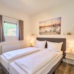 Zwei Einzelbetten mit weißen Bettwäschen, Wandbild und Nachttische mit Lampen.