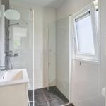 Badezimmer mit Dusche, Waschbecken und Fenster