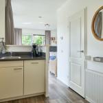 Küche mit Spüle, Kaffeemaschine und Blick in Wohnbereich.