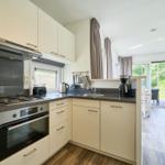 Küche mit weißen Schränken, Edelstahlherd und Blick auf Terrasse.