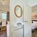 Zwei Schlafzimmer mit Betten, Fenster und Wandspiegel