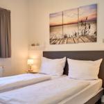 Zwei Einzelbetten mit weißen Bettwäschen und Wandbildern über dem Kopfteil.