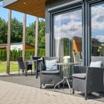 Terrasse mit Sitzgelegenheiten und Blick auf grünen Garten.