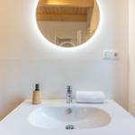 Waschbecken mit runder beleuchteter Spiegelfläche und Handtuch