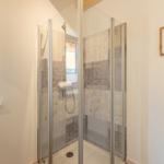 Duschbad mit Glaswand, Fenster und Wandbild.