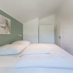 Schlafzimmer mit Bett, Wandbild und Schrank.