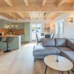 Wohn- und Essbereich mit Kücheninsel und Holzbalkendecke.