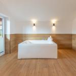 Bad mit Whirlpool, Holzfußboden und großem Fenster zur Terrasse.