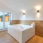 Bad mit Whirlpool, Holzwand und Fenster zur Terrasse.