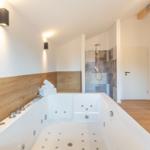 Bad mit Whirlpool und Dusche, Holzverkleidung und moderner Beleuchtung.