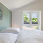 Schlafzimmer mit Bett, Fenster und Wandbild.