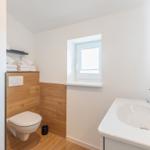 Badezimmer mit Toilette, Waschbecken und kleinem Fenster.