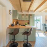 Küche mit Essbereich, Holzbalkendecke und modernen Hängelampen.