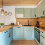 Küche mit Holzoberflächen, hellen Schränken und moderner Ausstattung.