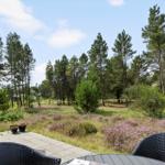 Terrasse mit Tischen und Stühlen, Blick auf einen Wald mit Heideflächen.