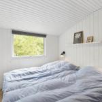 Schlafzimmer mit Bett, Fenster und Wandlampen. Weiße Holzwandverkleidung.