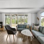 Wohnzimmer mit Sofa, Stühlen und Blick auf Wald.