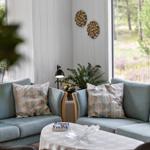 Ein Wohnzimmer mit zwei Sofas, Tisch und Pflanzen. Fenster zeigen Wald.