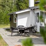 Terrasse mit Tisch und Stühlen vor einem Haus mit weißen Wänden und Schornstein.