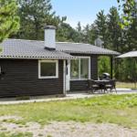 Ein dunkelholzverkleidetes Haus mit Terrasse, Grill und Sonnenschirm im Wald.