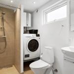 Badezimmer mit Dusche, Waschmaschine, WC und Waschbecken.