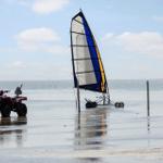 Ein Quad und ein Segelboot stehen im flachen Wasser.