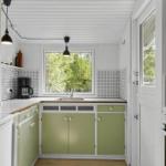 Küche mit grünen Schränken, Fenster und Küchenzeile.