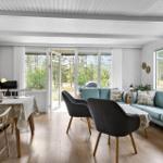 Wohn- und Essbereich mit Sofa, Stühlen und Tisch. Durchgang zur Terrasse mit Blick in den Wald.