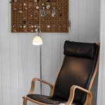 Schwarzer Ledersessel vor Holzregal mit Sammlerobjekten an weißen Wänden.