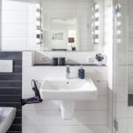 Badezimmer mit Waschbecken, Spiegel und Dusche. Schwarze und weiße Fliesen.