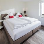 Schlafzimmer mit Doppelbett, zwei Nachttischen und Fenster.