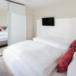 Schlafzimmer mit Doppelbett, Spiegelschrank und Wandfernseher.