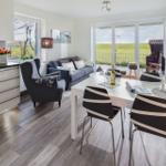 Wohn- und Essbereich mit Küchenzeile und Blick auf grüne Landschaft.