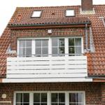 Haus mit rotem Ziegeldach, weißen Fenstern und Balkon