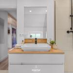 Bad mit Waschbecken, Dusche und Spiegel. Holzoberfläche und moderne Armaturen.