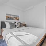 Schlafzimmer mit Bett, Wandbild und Nachttischen.