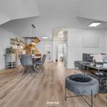 Wohn- und Essbereich mit Sofa, Esstisch und Küchenzeile unter Dachschrägen.