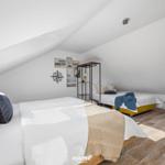 Zwei Betten unter Dachschrägen mit Fenster und Wanddekoration.