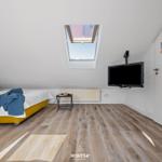 Schlafzimmer mit Dachschräge, Dachfenster, Bett und Wand-TV.